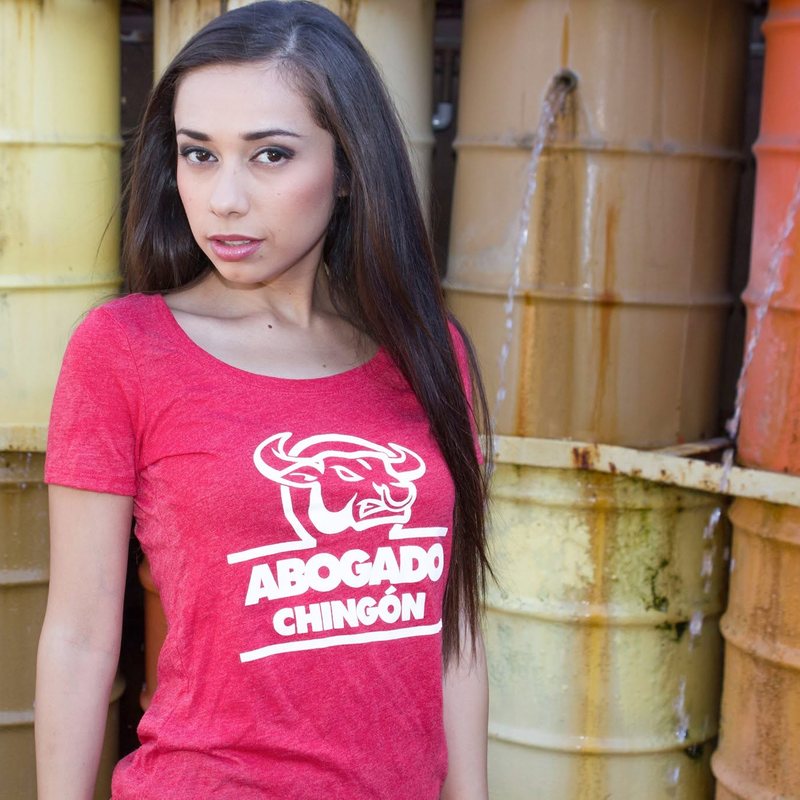 Model in a red Abogado Chingón tee in front of colorful barrels