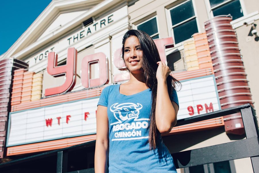 Model in a blue Abogado Chingón tee outside a theater